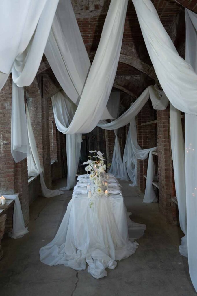 Table with floral decorations in a room with brick walls and white curtains