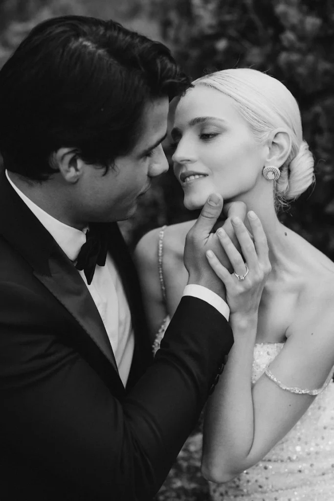 The groom places his hand on the bride's cheek and reaches out for a kiss