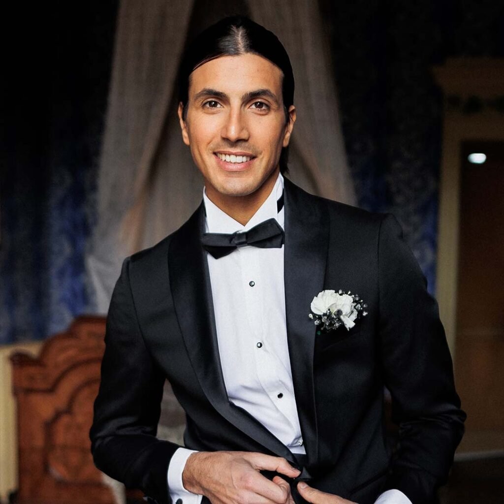 Front view of a guy model with long dark hair in a black suit