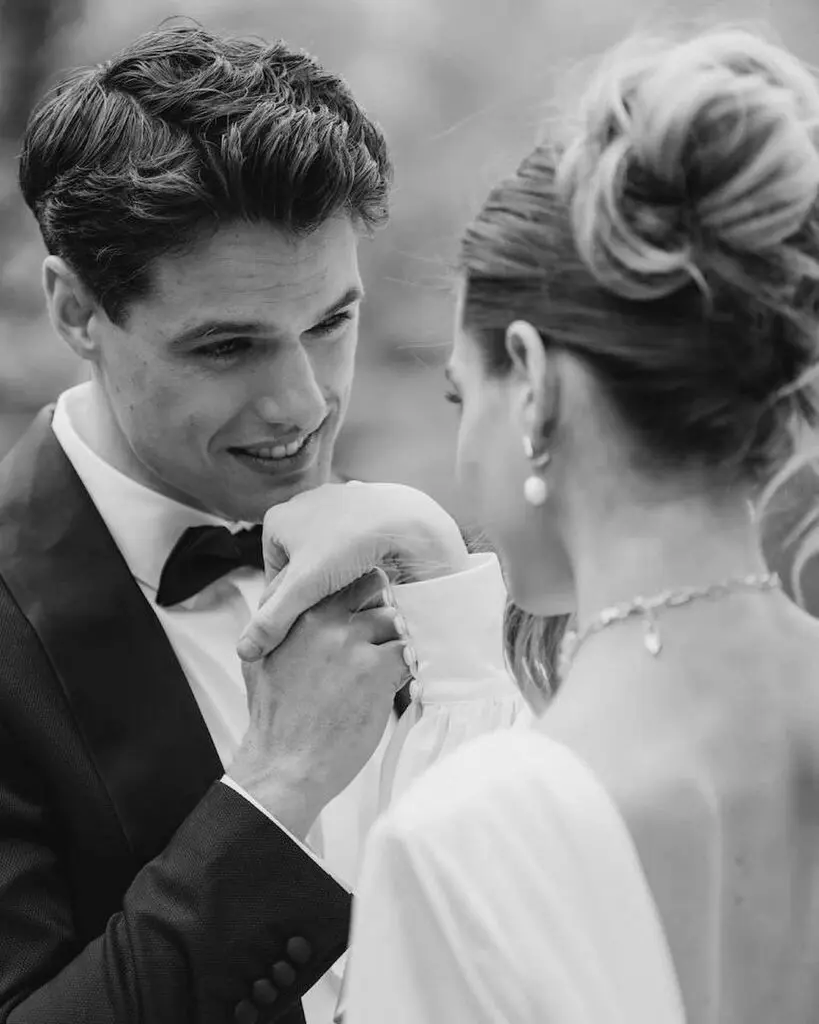 A black and white photo of the groom kissing the bride's hand and looking happily into her eyes