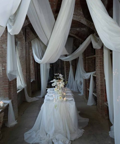 Table with floral decorations in a room with brick walls and white curtains