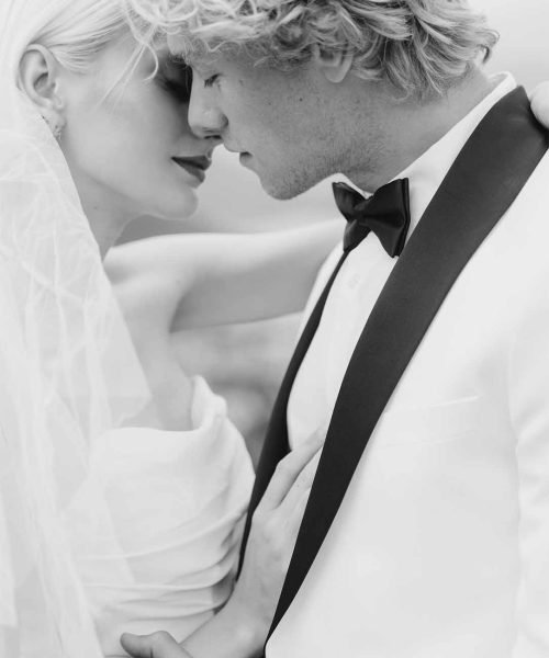 A close-up black and white photo of the bride and groom reaching for each other for a kiss