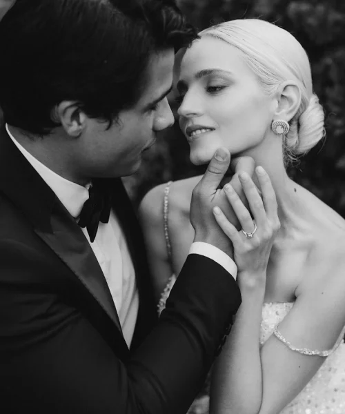 The groom places his hand on the bride's cheek and reaches out for a kiss